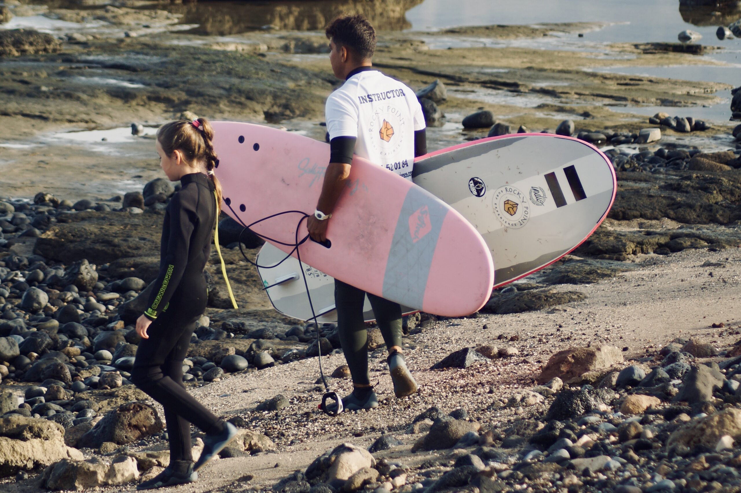 child entering the water with her surf instructor